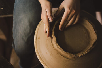 Hands skillfully shape a clay pot in a pottery studio. The workshop encourages creativity and focuses on teaching pottery techniques to beginners in a relaxed atmosphere.