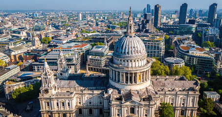 Aerial view of St. Paul’s Cathedral in London with surrounding cityscape under clear blue skies