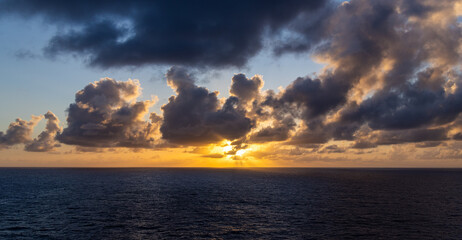 Obraz premium Dramatic Sunset over Ocean with Vibrant Clouds and Golden Horizon Glow