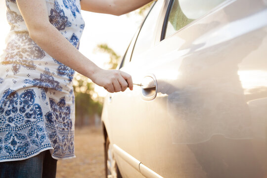 Young woman unlocking car on sunlit afternoon