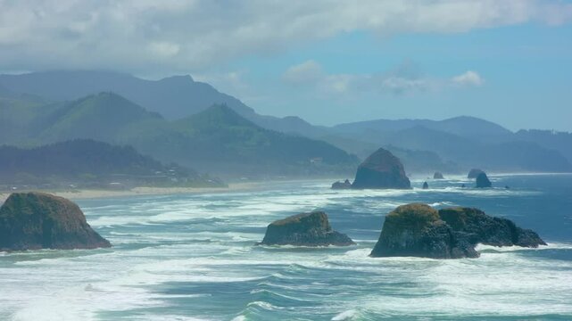 Footage depicts Oregon's Oswald West State Park, featuring crashing surf, massive rock formations, and dense coastal forest on a moody weather day.