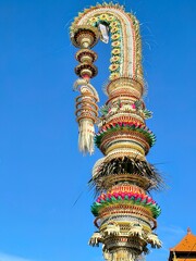 Penjor decoration in Bali, Indonesia made from colored coconut leaves, mounted on a bamboo tree...