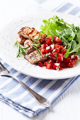 Fried pork tenderloin with tomato salsa. Bright background. Close up.	