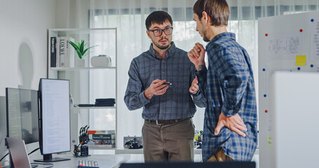 Obraz premium Team adult male engineer collaborate on robotic hand project using AI code solutions machine learning at tech workspace. Artificial intelligence interface, collaboration support prototype development.