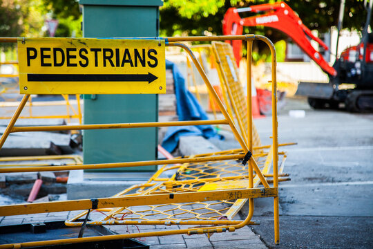 Pedestrians this way sign with barrier fence at worksite