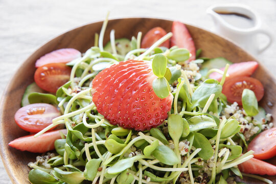 Sunflower sprouts and strawberries salad on wooden bowl