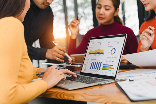 Business team working on data analysis project with laptop showing charts and graphs, discussing strategy in modern office, teamwork and collaboration concept