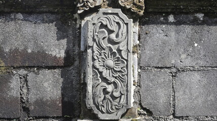 Intricate Stone Carving Ancient Floral Design on Grey Brick Wall