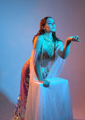 Fantasy studio portrait of a red-haired mermaid faery model wearing white pearl gown, fairytale...
