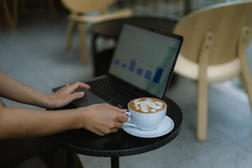 Freelance woman holding a cup of coffee and using a laptop