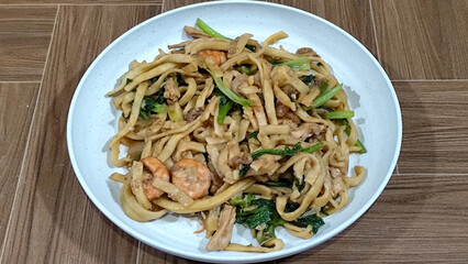 Fried noodles with vegetables and shrimp, looks very delicious served on a plate.