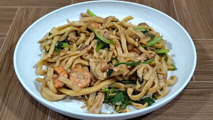 Fried noodles with vegetables and shrimp, looks very delicious served on a plate.