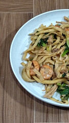 Fried noodles with vegetables and shrimp, looks very delicious served on a plate.