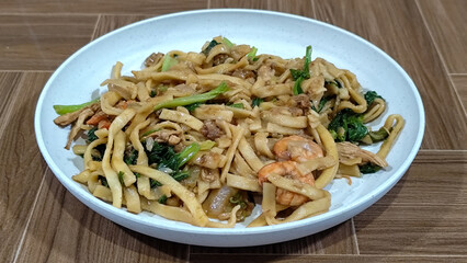 Fried noodles with vegetables and shrimp, looks very delicious served on a plate.
