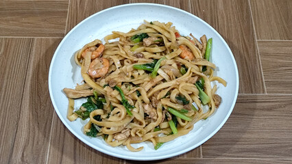 Fried noodles with vegetables and shrimp, looks very delicious served on a plate.