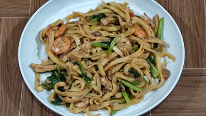 Fried noodles with vegetables and shrimp, looks very delicious served on a plate.