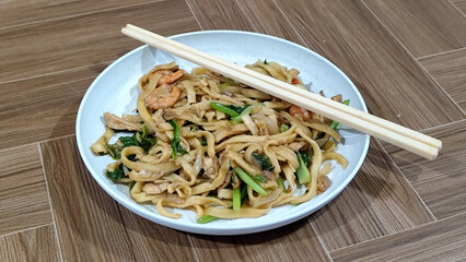 Fried noodles with vegetables and shrimp, looks very delicious served on a plate.