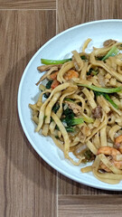 Fried noodles with vegetables and shrimp, looks very delicious served on a plate.
