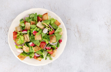 Lebanese fattoush salad with fresh vegetables, romaine lettuce and pita bread on white background. Top view. Copy space