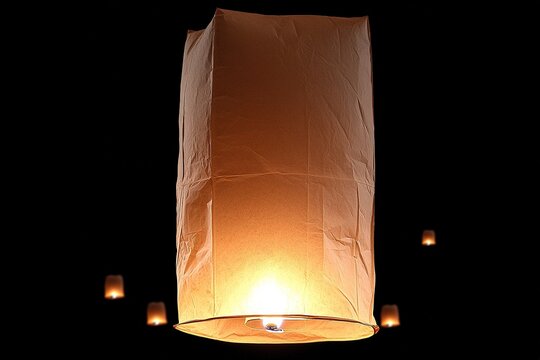 Floating lanterns shine in dark sky