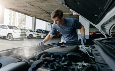 Man inspecting smoking car engine in parking garage