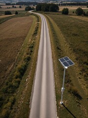 A solar panel is on top of a pole beside an empty road.