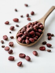 A spoon filled with unshelled red peanuts.