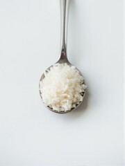 A spoon filled with white rice on top of table.