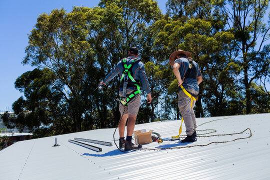 Electrician tradesmen workers on house roof discussing installing solar panel system together