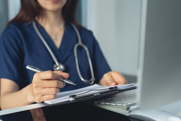 Fototapeta premium Doctor wrting medicine prescription on clipboard and working on desktop computer pc at doctor's office in hospital, treatment plan. Doctor working at office, filling insurance document