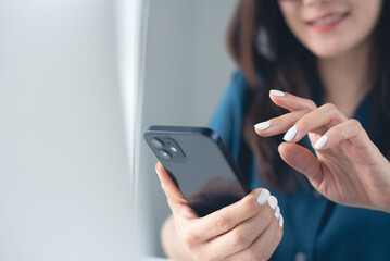 Smiling asian woman using smartphone at home