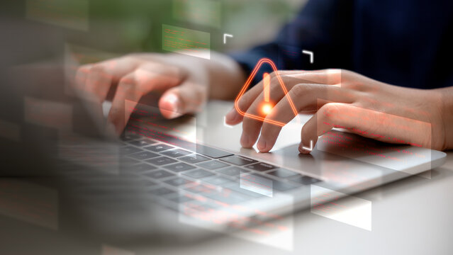 Close-up hands typing on laptop with warning sign and digital error codes on screen, representing cybersecurity threats, system failure, malware, and data breach issues. - Powered by Adobe
