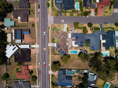 Sunlit street in suburbs with t intersection and houses alongside road