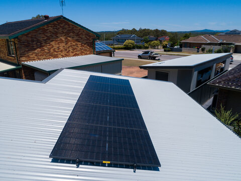 Aerial view of house in small lot of land with newly installed mini solar system on roof of house