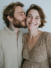 A close-up of a man kissing the belly of his wife who is pregnant with their child.