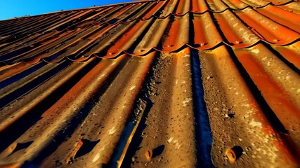 Weathered and rusted orange metal roof panels create abstract pattern against vibrant blue sky backdrop. - Powered by Adobe