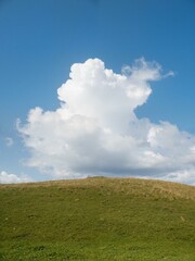 Clouds loom over grassy hill.