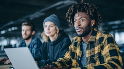 Obraz premium Three diverse people look at a laptop screen indoors in a casual setting.