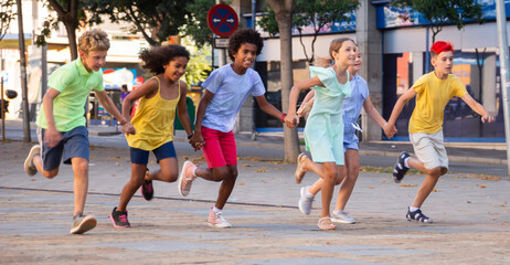 Obraz premium Group of smiling kids holding each other hands while running through city streets together.