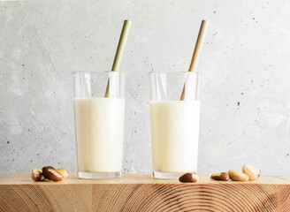 Brazil nut milk served in two clear glasses with golden straws, placed on a wooden surface, surrounded by scattered nuts, creating a fresh and inviting atmosphere for healthy living