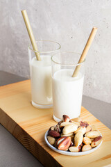 Brazil nut milk served in clear glasses with eco-friendly straws, accompanied by a plate of assorted nuts, creating a natural and healthy snack presentation on a wooden board