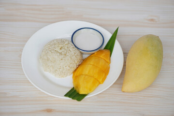 Homemade glutinous rice with ripe mango and coconut milk on dish. Concept, traditional Thai sweet dessert made from mangoes. Perfect for Asian cuisine and tropical food theme, ideal for culinary use.
