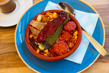Migas with roasted pepper and pieces of chorizo served on table in restaurant.