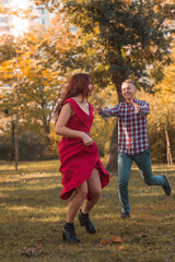Fototapeta premium young couple in love actively relaxing in autumn park. they are running, having fun and laughing