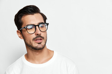 Fototapeta premium Stylish young man wearing glasses, looking thoughtfully at the camera with a serious expression, isolated on a plain solid background. People lifestyle concept.