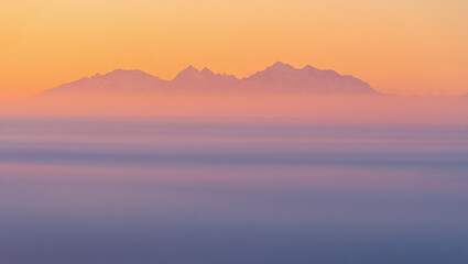 Fototapeta premium Mountain range at sunrise with mist and colorful sky