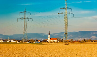 Spring landscape with a church, the Bavarian Forest in the background and overland high voltage...