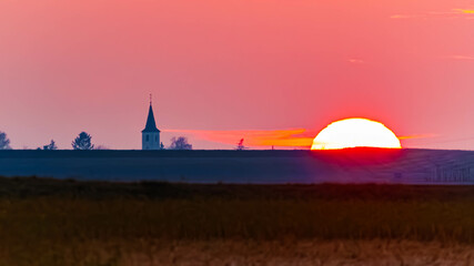 Obraz premium Sunset or sundowner with a church silhouette near Osterhofen, Danube, Deggendorf, Bavaria, Germany
