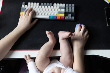 A person works at a computer, typing on a colorful keyboard with one hand while using a mouse with...