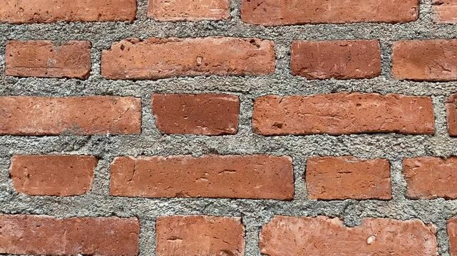 Orange brick wall with cement lines showing rough texture and horizontal construction pattern
